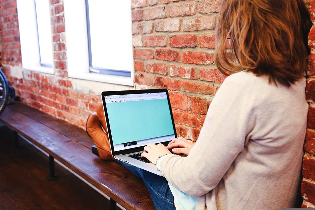 woman using laptop on bench set up your soap business profile